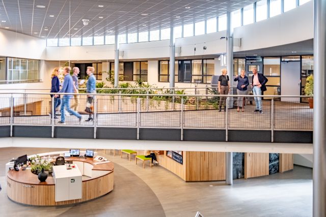 Ingang gemeentehuis. Mensen lopen over de loopbrug heen.